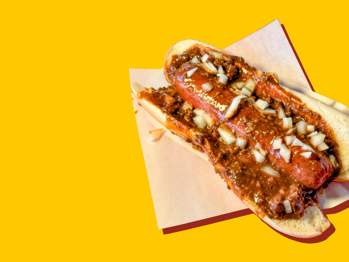 An all-beef chili dog smothered in chili and diced onions, on deli paper