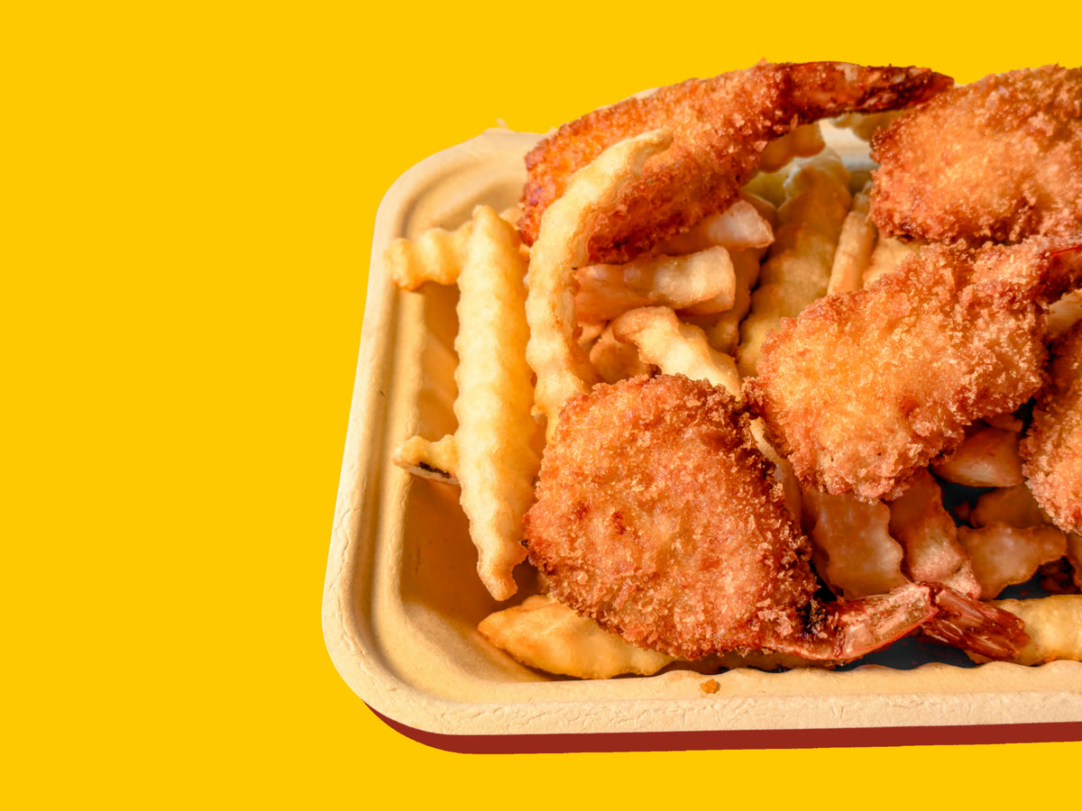 Breaded butterflied shrimp on crinkle-cut fries in a paper tray